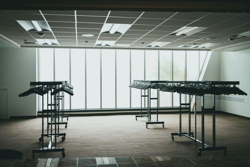 Empty room with metal clothing racks and large windows in a modern setting.