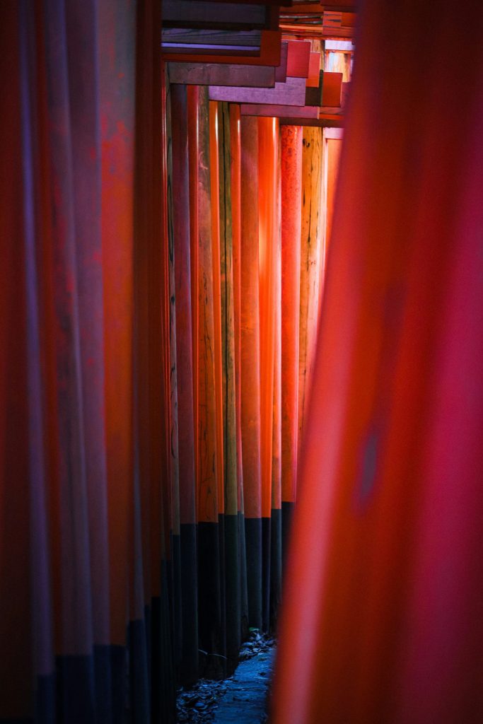 A row of red and black poles next to a body of water